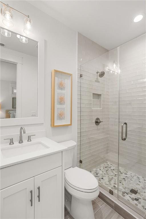 full bathroom featuring a stall shower, vanity, and toilet