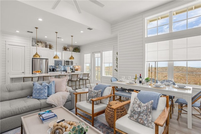 living area featuring light wood-type flooring, ceiling fan, visible vents, and recessed lighting