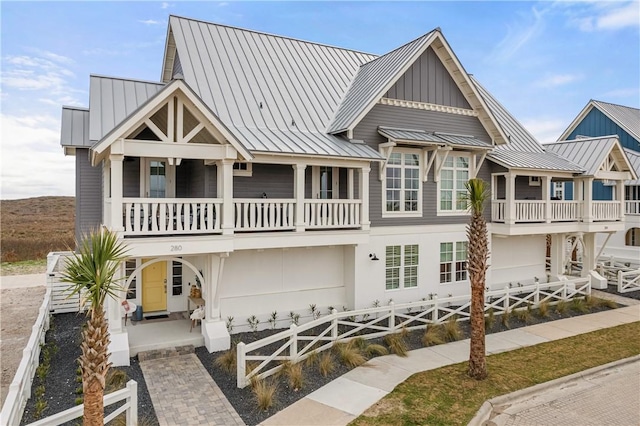 rear view of property featuring metal roof, a standing seam roof, board and batten siding, and a fenced front yard