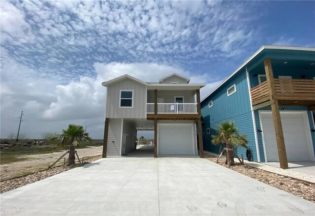  - coastal inspired home featuring an attached garage, driveway, a balcony, and board and batten siding