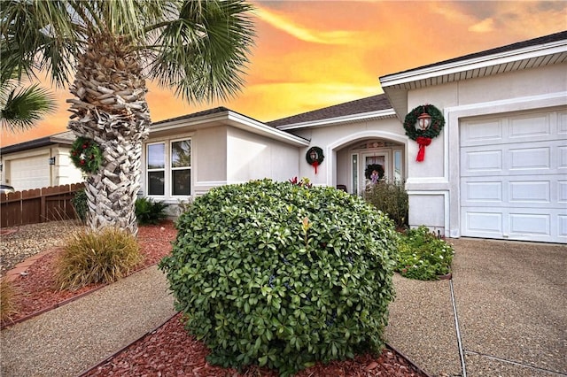 13805 Hawksnest Bay Dr, Corpus Christi, TX 78418 - exterior entry at dusk featuring an attached garage and stucco siding