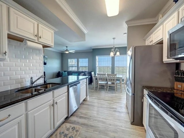 kitchen featuring crown molding, white cabinets, tasteful backsplash, a sink, and appliances with stainless steel finishes