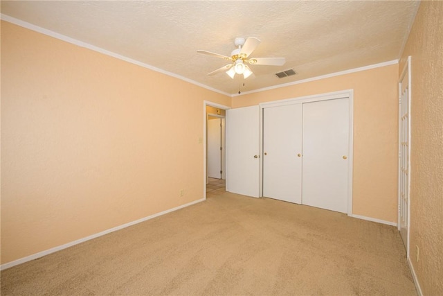 unfurnished bedroom featuring light carpet, crown molding, a closet, and a textured ceiling