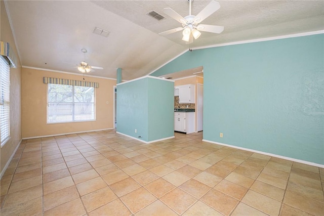 tiled empty room with crown molding, lofted ceiling, a textured ceiling, and ceiling fan