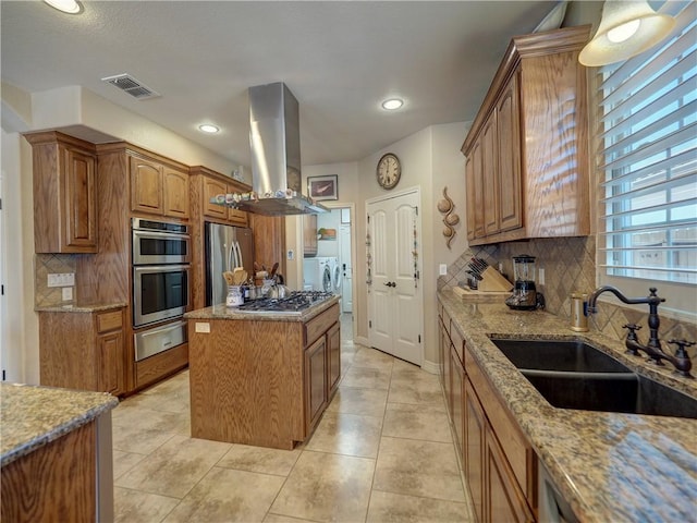 13834 Captains Row, Corpus Christi, TX 78418 - kitchen featuring ventilation hood, a warming drawer, washing machine and dryer, stainless steel appliances, and light stone counters