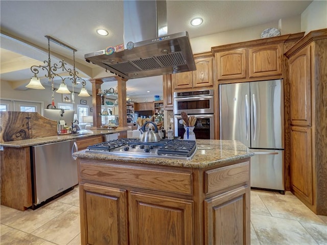 13834 Captains Row, Corpus Christi, TX 78418 - kitchen featuring stainless steel appliances, wall chimney range hood, a center island, light stone countertops, and brown cabinetry