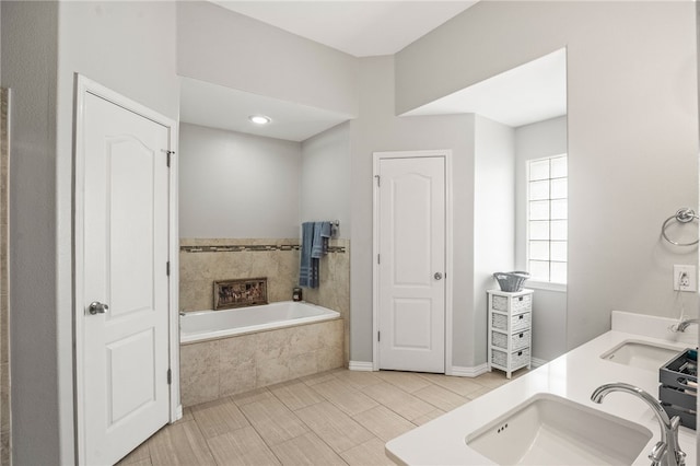 bathroom with vanity and tiled tub