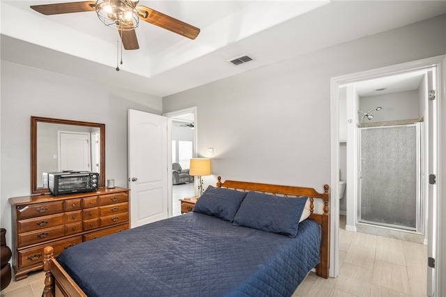 bedroom featuring connected bathroom, ceiling fan, and a raised ceiling