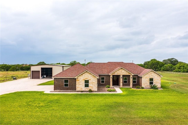 view of front facade with a detached garage, an outbuilding, stone siding, and a front yard