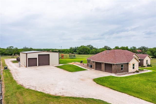 exterior space featuring a yard, an outbuilding, stone siding, and a detached garage