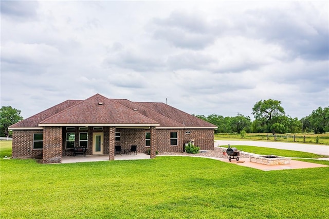 back of house featuring a lawn, a patio, and a fire pit