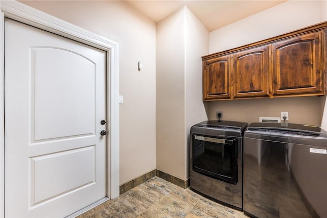 washroom featuring cabinet space, separate washer and dryer, baseboards, and stone finish flooring