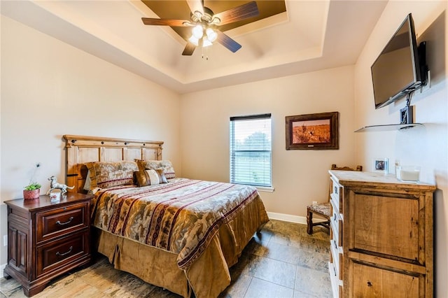 bedroom featuring baseboards, a ceiling fan, and a tray ceiling