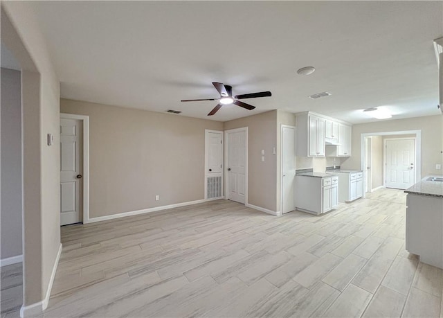 kitchen featuring white cabinets, ceiling fan, light hardwood / wood-style floors, and light stone countertops