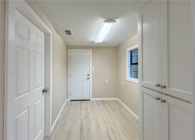 corridor with light hardwood / wood-style flooring and a textured ceiling