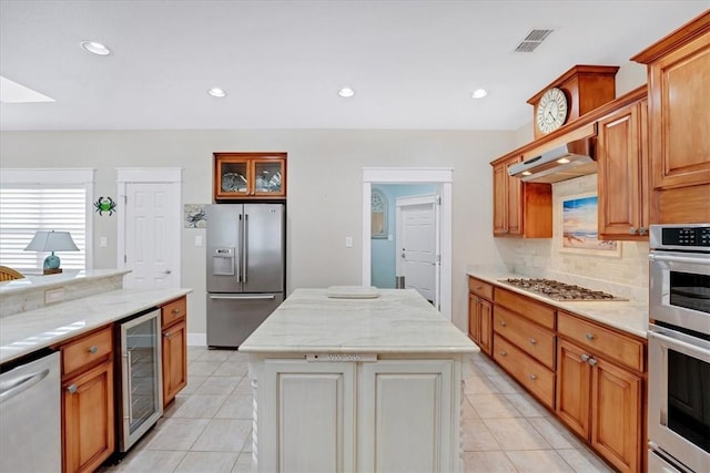 kitchen featuring appliances with stainless steel finishes, light tile patterned flooring, a kitchen island, and wine cooler