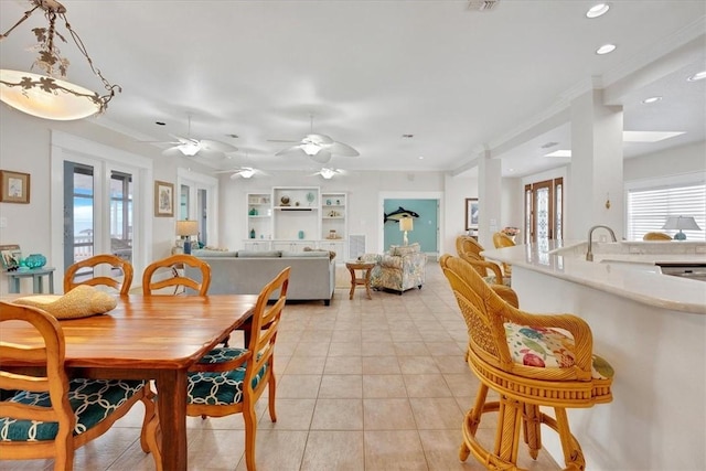 dining area featuring sink, light tile patterned floors, ornamental molding, and plenty of natural light