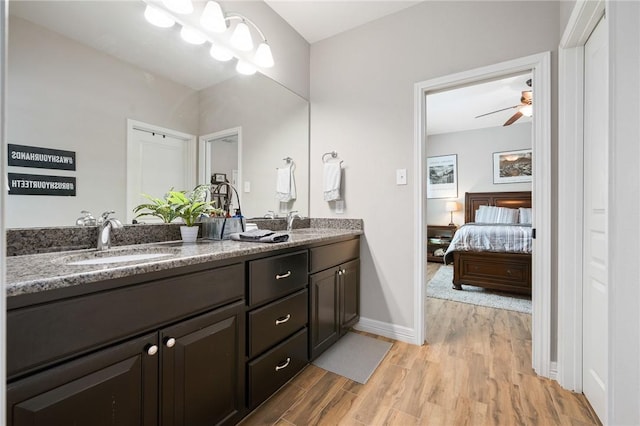 116 James Dr, Sinton, TX 78387 - bathroom featuring wood finished floors, double vanity, ceiling fan, baseboards, and ensuite bath