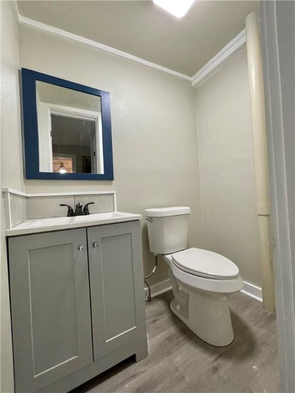 bathroom featuring vanity, toilet, wood-type flooring, and crown molding