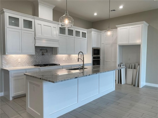 13941 Flintlock Dr, Corpus Christi, TX 78418 - kitchen featuring stainless steel appliances, white cabinets, decorative backsplash, a center island with sink, and recessed lighting