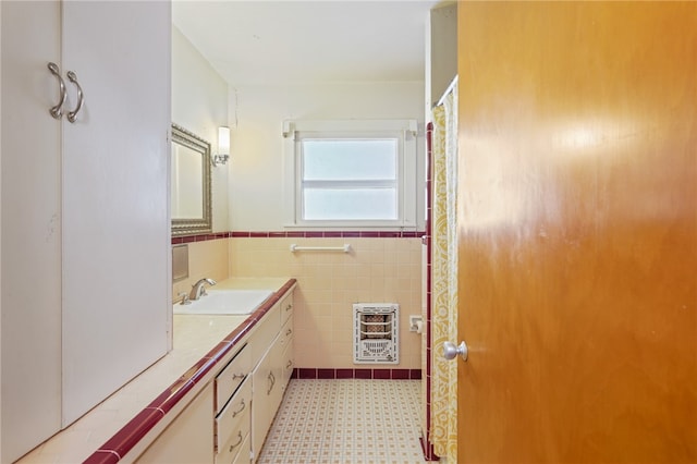 bathroom with vanity, heating unit, and tile walls