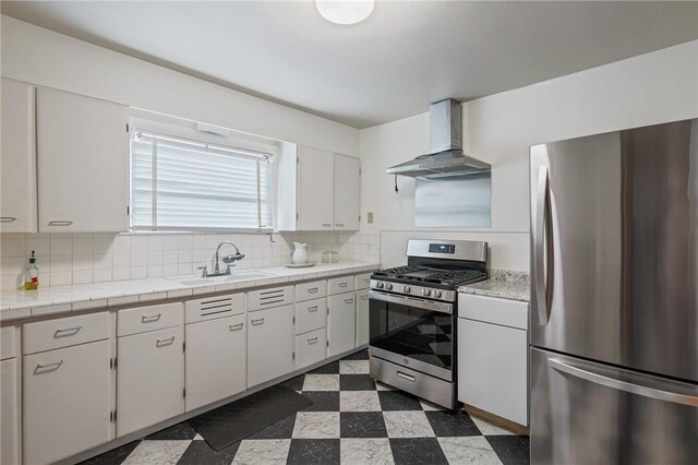 kitchen with sink, white cabinets, wall chimney range hood, and appliances with stainless steel finishes