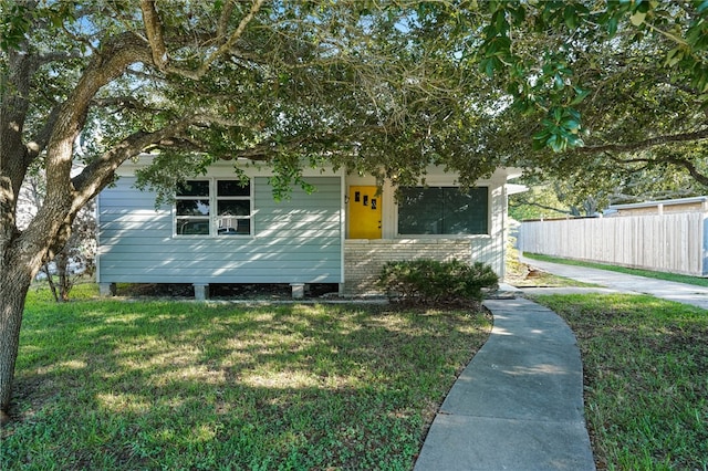 view of property hidden behind natural elements featuring a front lawn