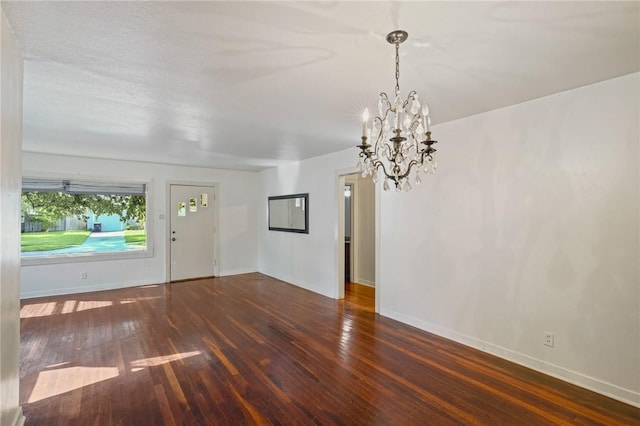 empty room featuring a textured ceiling, dark wood-type flooring, and wood walls