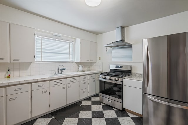 kitchen with wall chimney exhaust hood, white cabinetry, sink, and appliances with stainless steel finishes