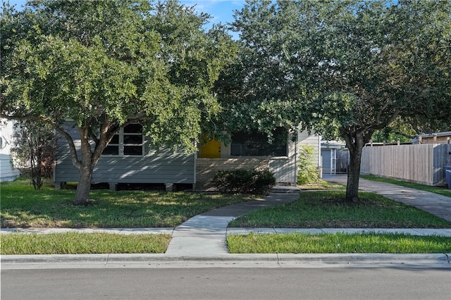 view of property hidden behind natural elements featuring a front yard