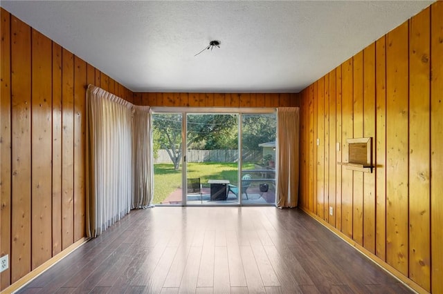 unfurnished room with ceiling fan, dark wood-type flooring, and wood walls