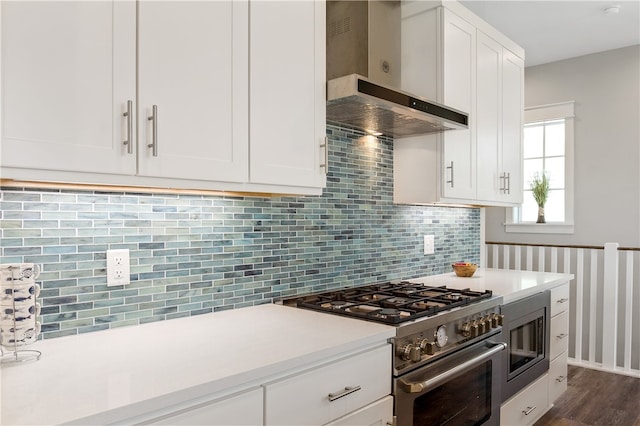 kitchen with white cabinetry, appliances with stainless steel finishes, wall chimney exhaust hood, backsplash, and dark hardwood / wood-style flooring