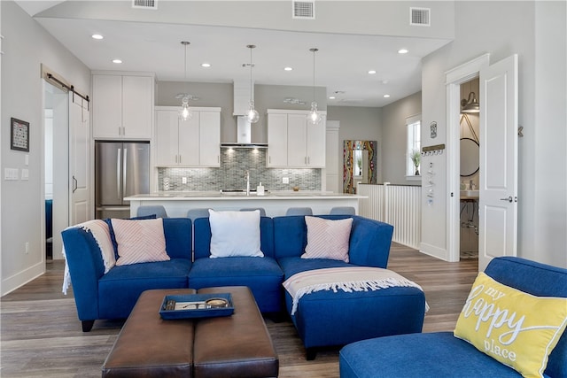 living room with a barn door, hardwood / wood-style flooring, and sink