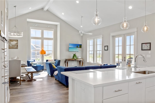 kitchen featuring french doors, white cabinets, sink, light wood-type flooring, and decorative light fixtures