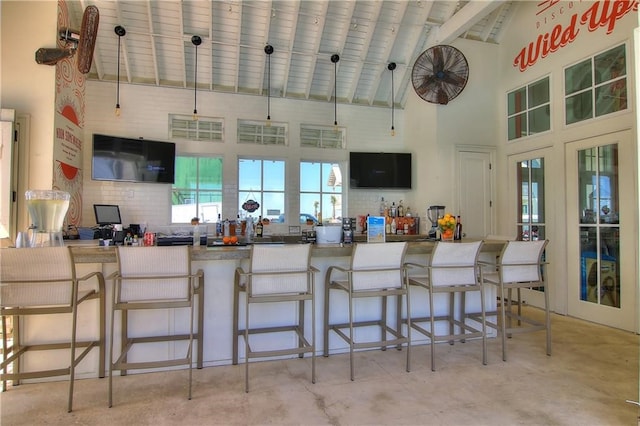 kitchen with kitchen peninsula, a kitchen breakfast bar, decorative light fixtures, and high vaulted ceiling