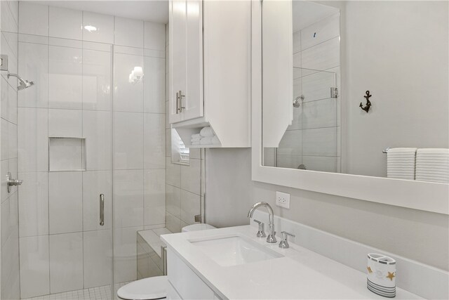 bathroom with toilet, vanity, and a shower with shower door