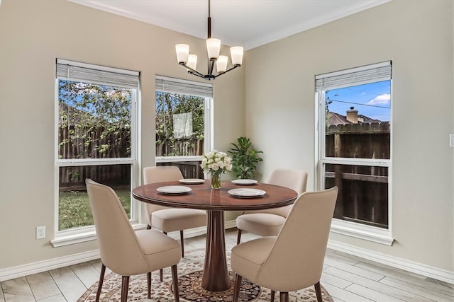 dining room with an inviting chandelier, plenty of natural light, crown molding, and light hardwood / wood-style flooring