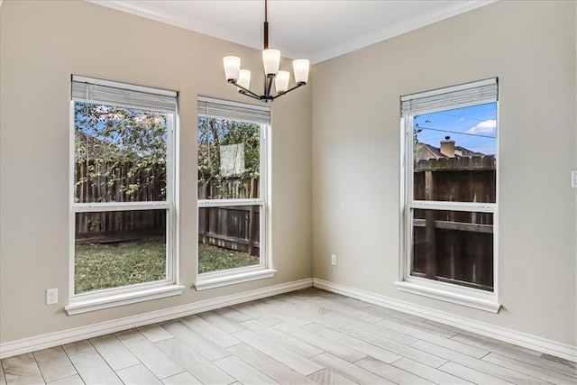 unfurnished dining area with crown molding, a wealth of natural light, a chandelier, and light hardwood / wood-style flooring