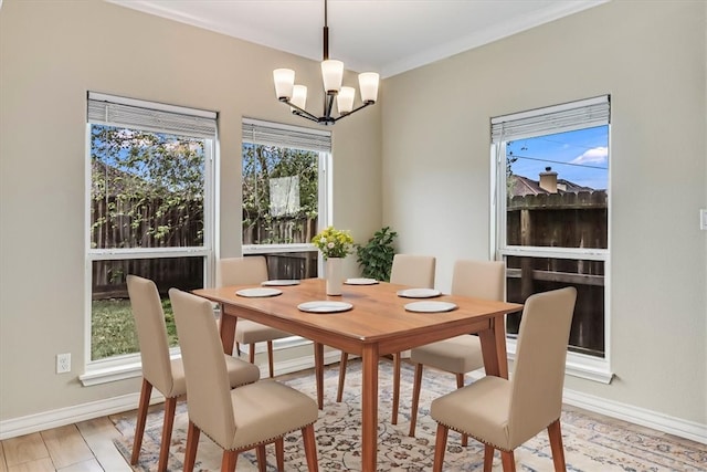 dining space with a healthy amount of sunlight, ornamental molding, a chandelier, and light hardwood / wood-style flooring