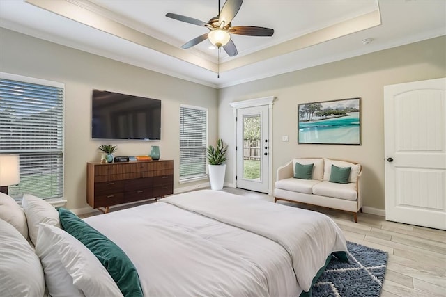 bedroom with a raised ceiling, ornamental molding, access to exterior, and light wood-type flooring