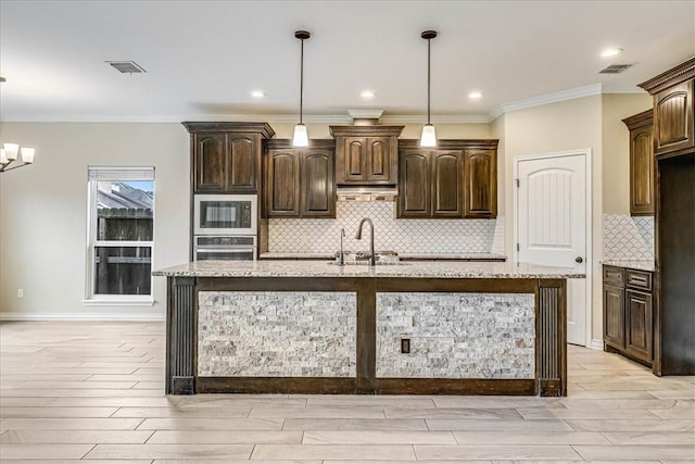 kitchen with black microwave, dark brown cabinets, a kitchen island with sink, and oven