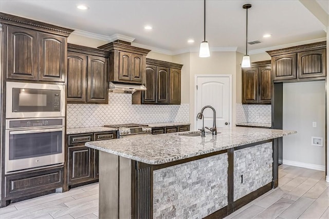 kitchen featuring appliances with stainless steel finishes, sink, a kitchen island with sink, and dark brown cabinets