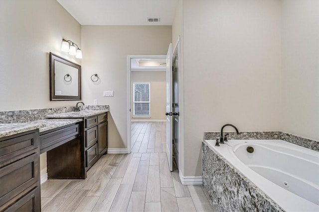 bathroom with tiled tub and vanity