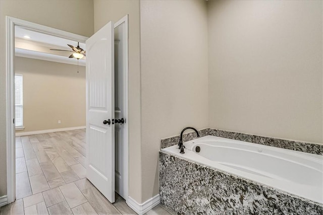 bathroom with tiled tub and ceiling fan