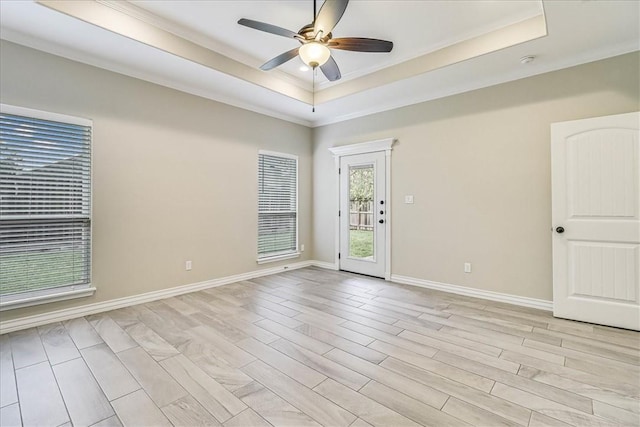 spare room with a raised ceiling, ornamental molding, ceiling fan, and light hardwood / wood-style floors