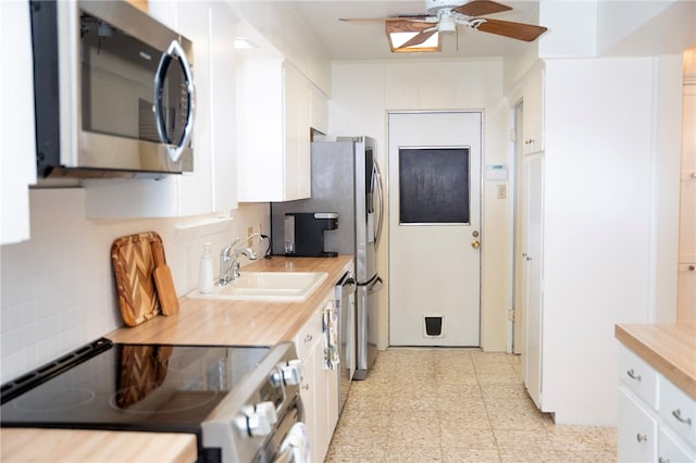 kitchen with tasteful backsplash, appliances with stainless steel finishes, a sink, and white cabinets