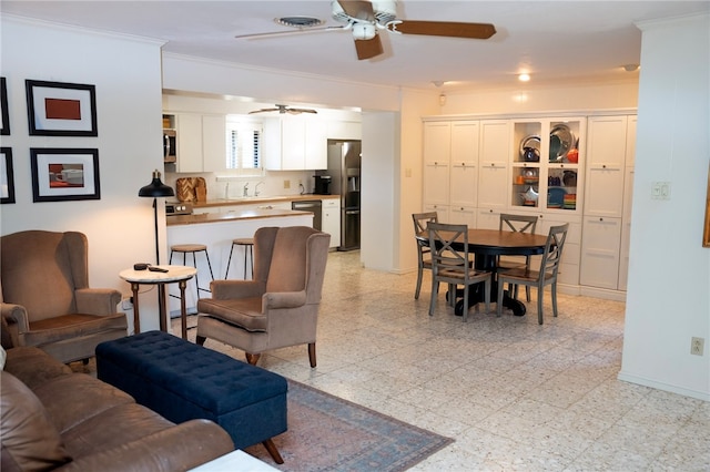 living area featuring a ceiling fan, baseboards, light floors, and crown molding