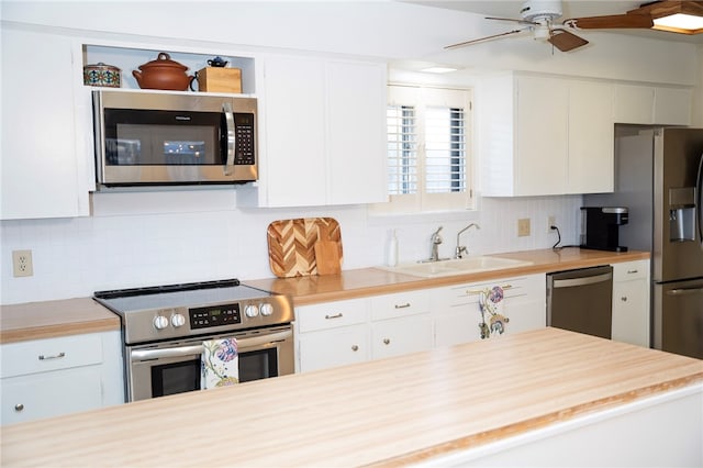 kitchen with stainless steel appliances, tasteful backsplash, a sink, and white cabinets