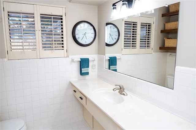 half bath featuring wainscoting, vanity, toilet, and tile walls