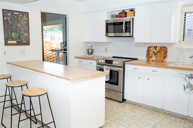 kitchen featuring a breakfast bar, tasteful backsplash, white cabinets, and stainless steel appliances